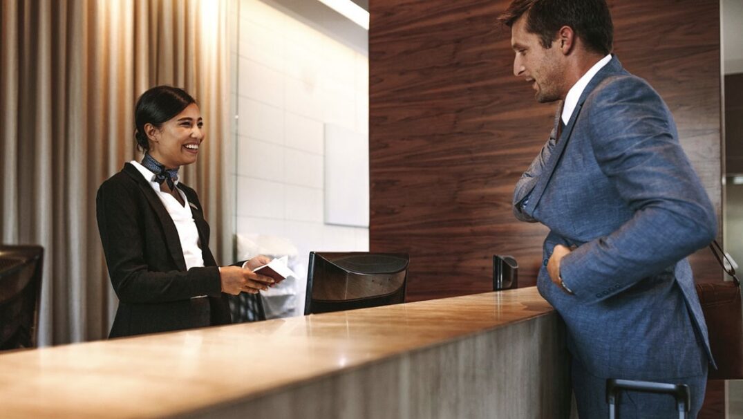 A man in a suit stands near the reception desk at a hotel
